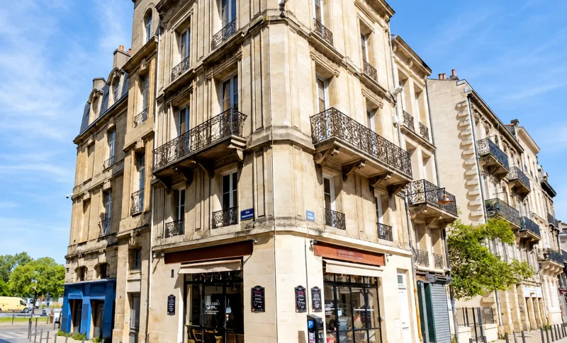 Immeuble d’angle en pierre et balcons du programme Rue des Faures à Bordeaux